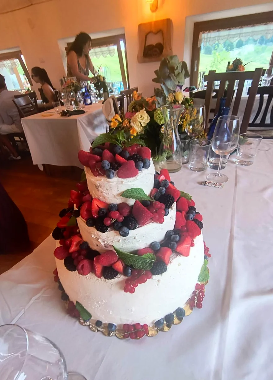 Torta a due piani con panna e frutti di bosco, servita su un tavolo apparecchiato
