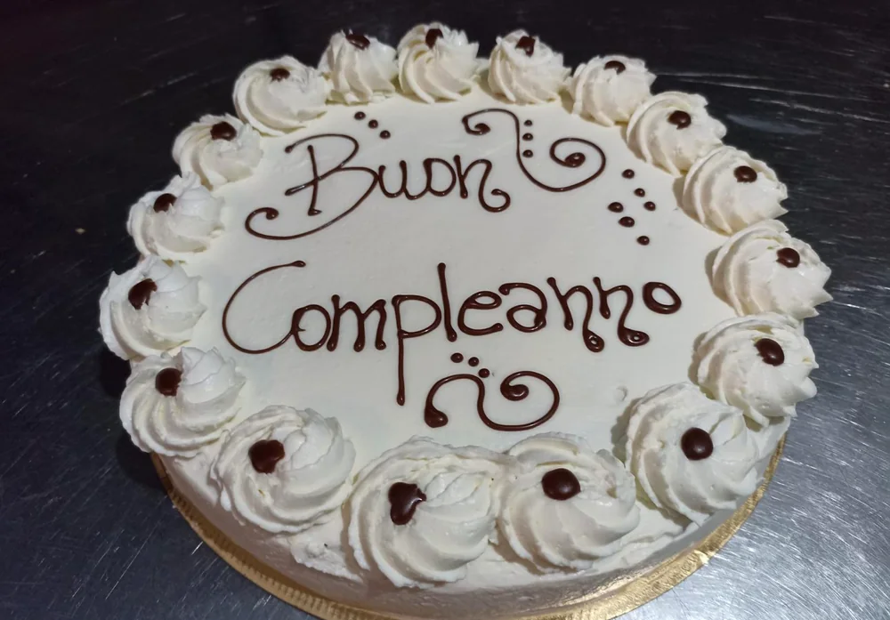 Torta classica con scritta Buon Compleanno in cioccolato e ciuffi di panna