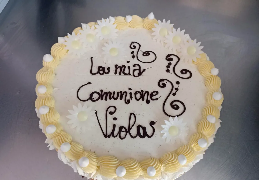 Torta per la comunione decorata con margherite di zucchero e scritta in cioccolato